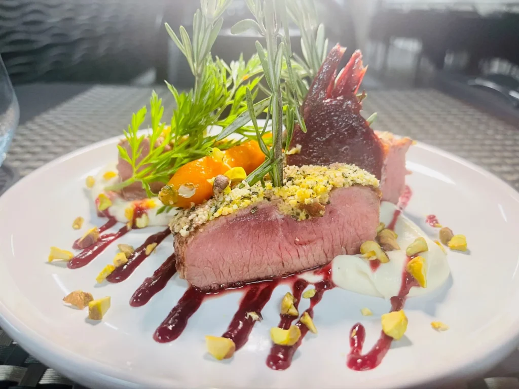 Pistachio and herb-crusted loin, sliced, with carrots and berry sauce