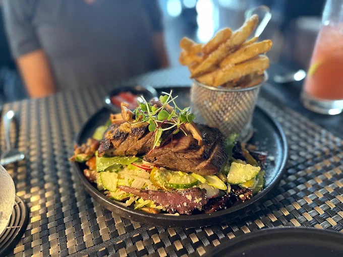 Grilled steak over salad with a basket of Parmesan fries