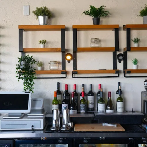 Wine bottles and plants on the shelves behind the counter